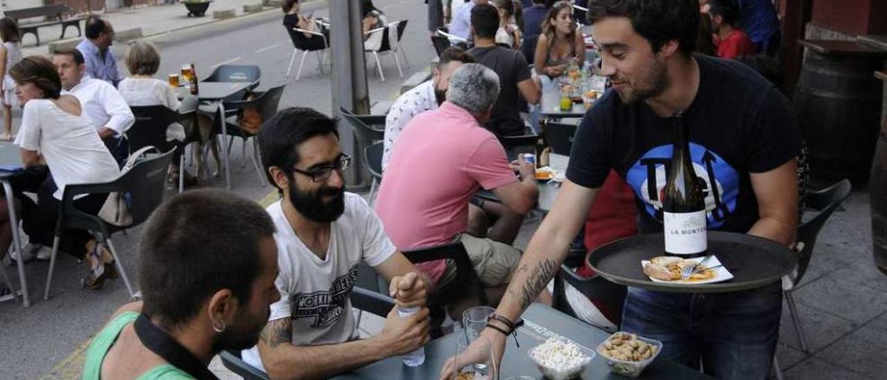 Un camarero atiende a unos clientes en una terraza de la calle Rosalía de Castro. // Bernabé/Javier Lalín
