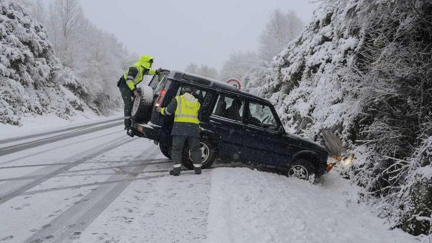 Agentes de la Guardia Civil ayudan a un conductor que se salió de la vía en Montederramo. // Brais Lorenzo