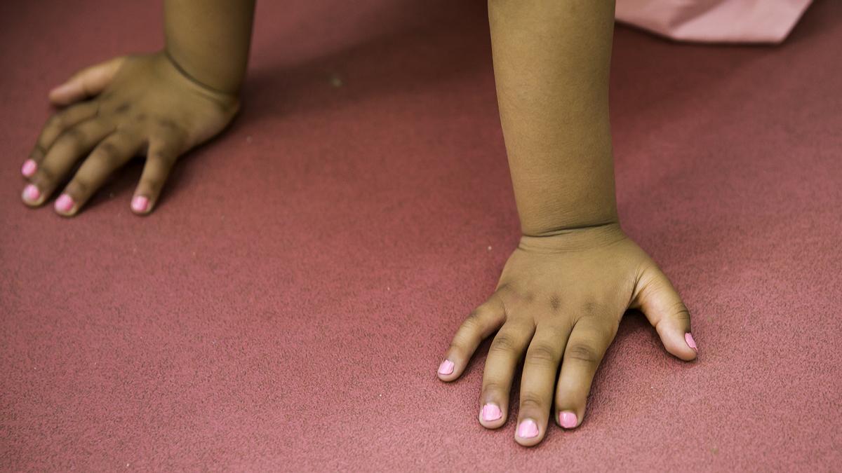Las manos de un niño y de una niña de la clase, pintadas de rosa