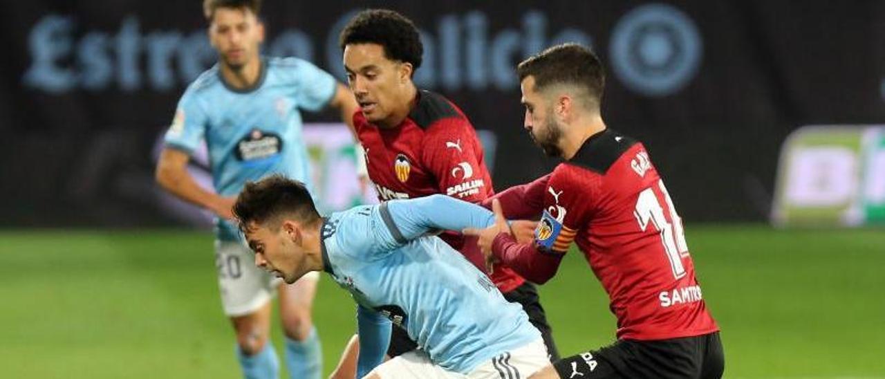 Fran Beltrán avanza con la pelota mientras es sujetado por Gayá durante el partido disputado anoche en Balaídos entre el Celta y el Valencia.