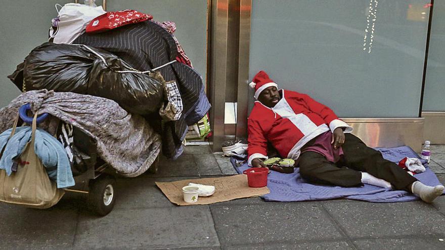 Un hombre vestido de San Claus duerme en la calle. Foto Efe