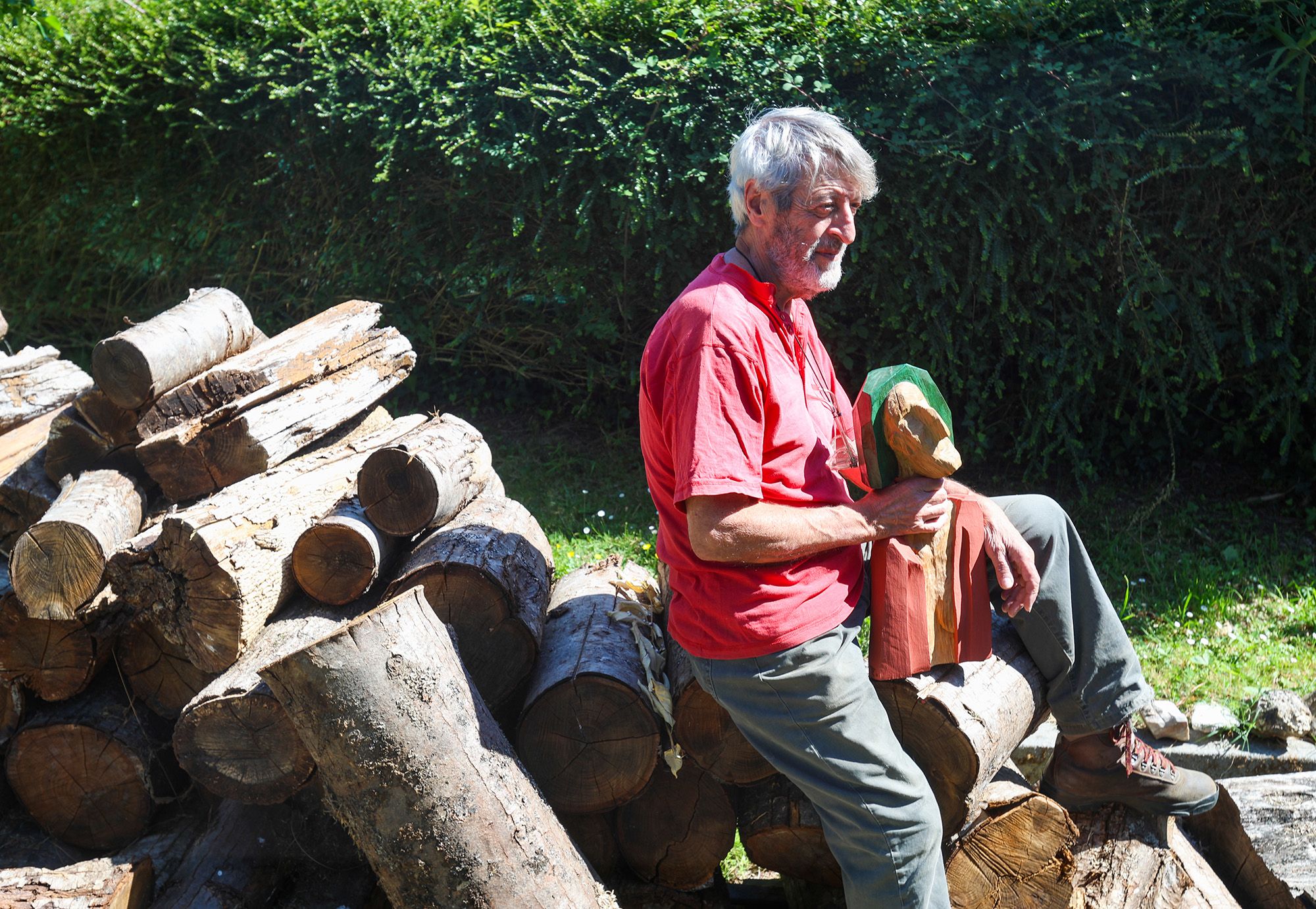 El artista con una de sus piezas sobre los troncos apilados que convertirá en esculturas.