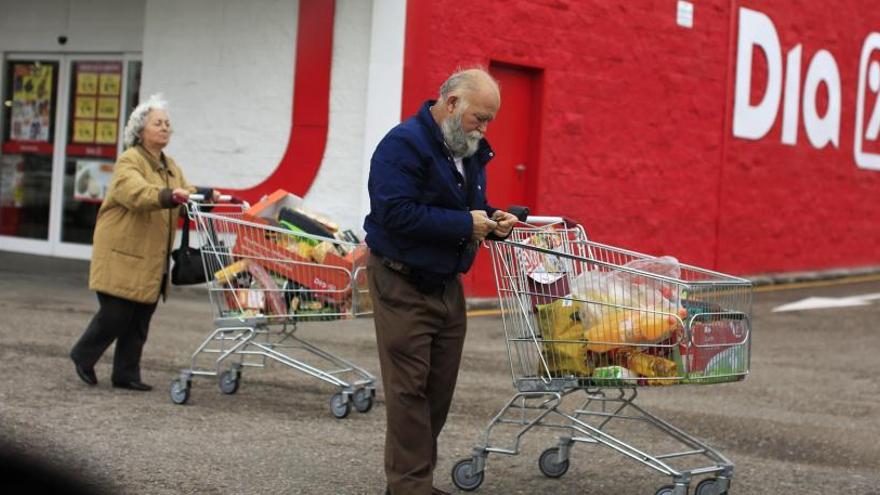 Dos personas salen de un supermercado con la compra.
