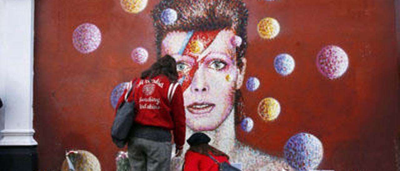 Dos mujeres dejan flores ante un mural de Bowie en Londres, ayer.