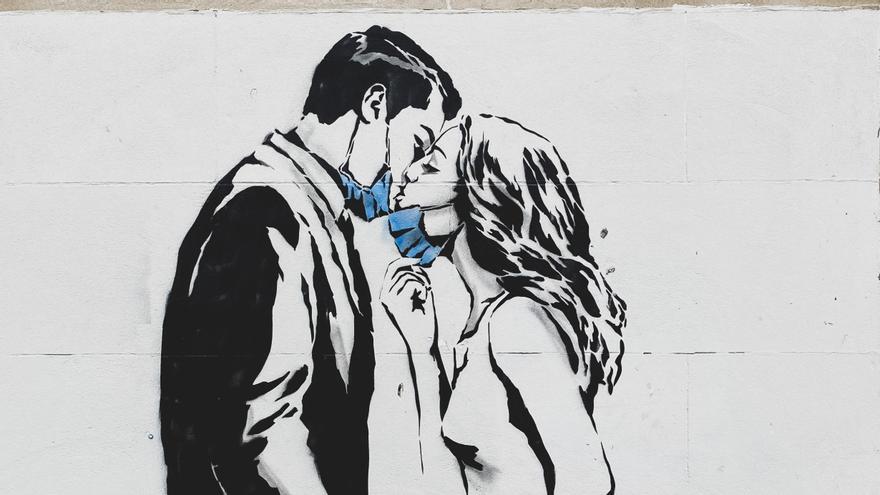 Graffiti que muestra a una pareja bajándose la mascarilla para besarse