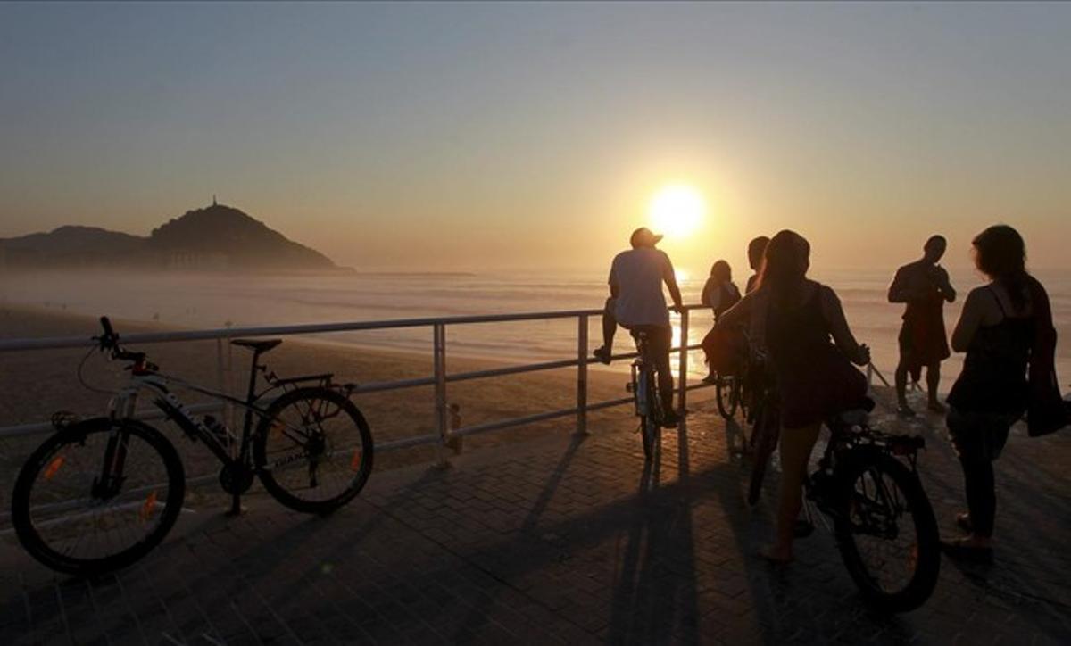 Donostiarras y visitantes disfrutan del atardecer en la playa de la Zurriola de San Sebastián, después de una jornada de intenso calor.