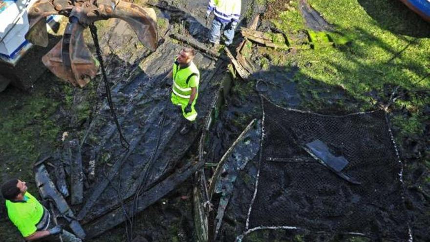 Los operarios de Portos retiran los restos del fondo de una embarcación abandonada.  // Iñaki Abella