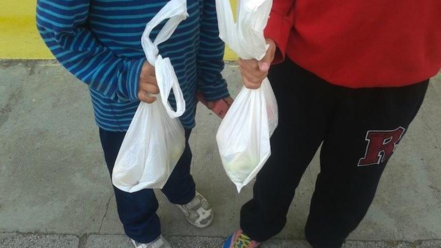 Dos alumnos vuelven a sus casas con las bolsas de la merienda que han recibido en sus colegios.