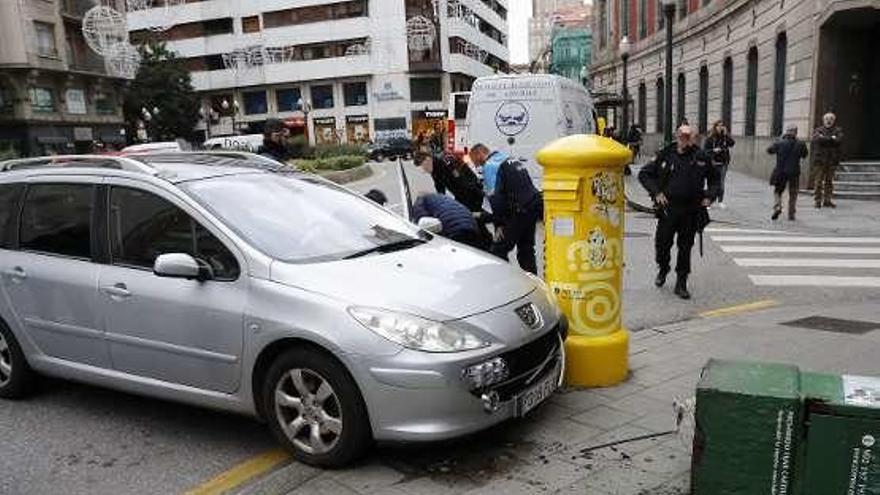 Agentes de la Policía, tras el vehículo siniestrado, auxilian al conductor que sufrió el desvanecimiento.