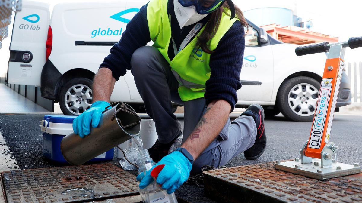 Un técnico toma una muestra de agua residual en busca de covid