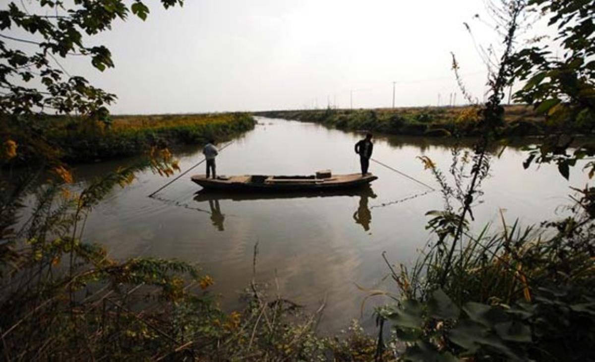 Habitants locals remen cap a la vora en un rierol de la vila de Huanglou, una part rural de Xangai on es construirà un nou parc temàtic Disney. Habitants locals remen cap a la vora en un rierol de la vila de Huanglou, una part rural de Xangai on es construirà un nou parc temàtic Disney.