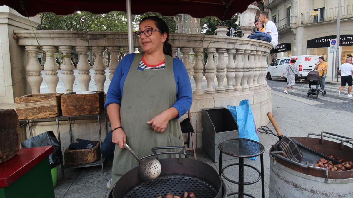 La Mercedes coent castanyes a la Rambla i, a la dreta, l’Espe preparant una paperina a la plaça de la Palmera