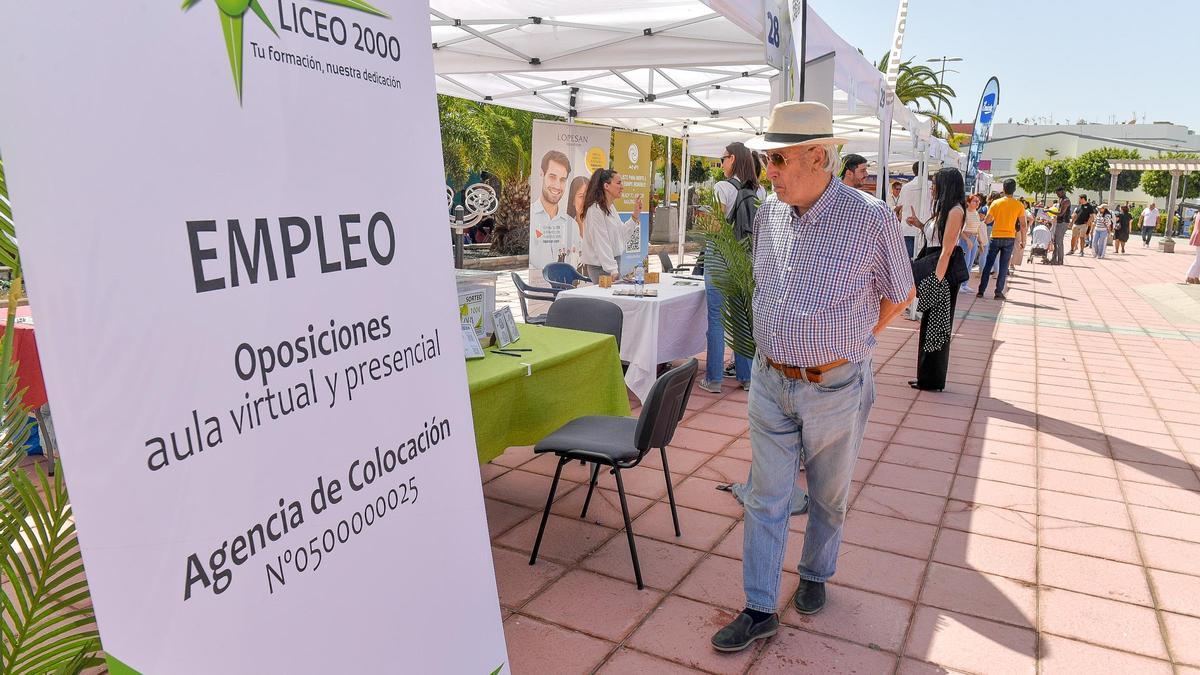 Un hombre mira los folletos informativos de uno de los estands de una muestra de empleo en Canarias.
