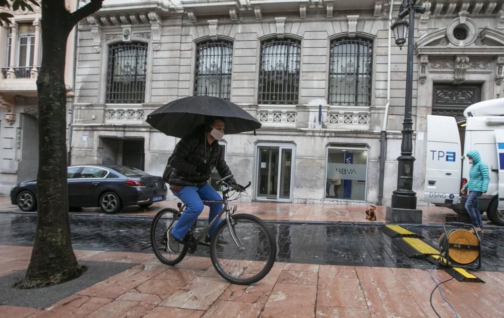 Un ciclista bajo la lluvia, ayer, en una calle de Oviedo.