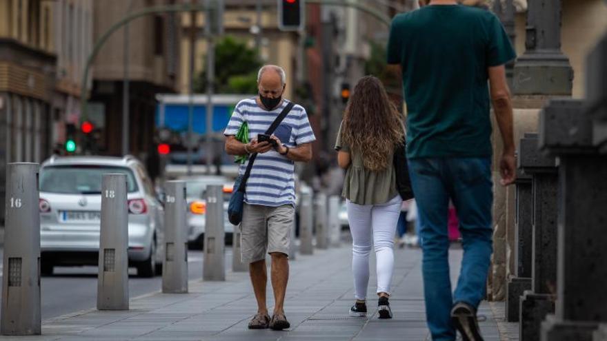 Un hombre pasea por el centro de Santa Cruz mirando su teléfono móvil.