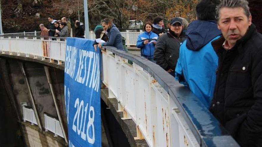 Miembros de Pladever tras colocar la pancarta en la presa. // FdV