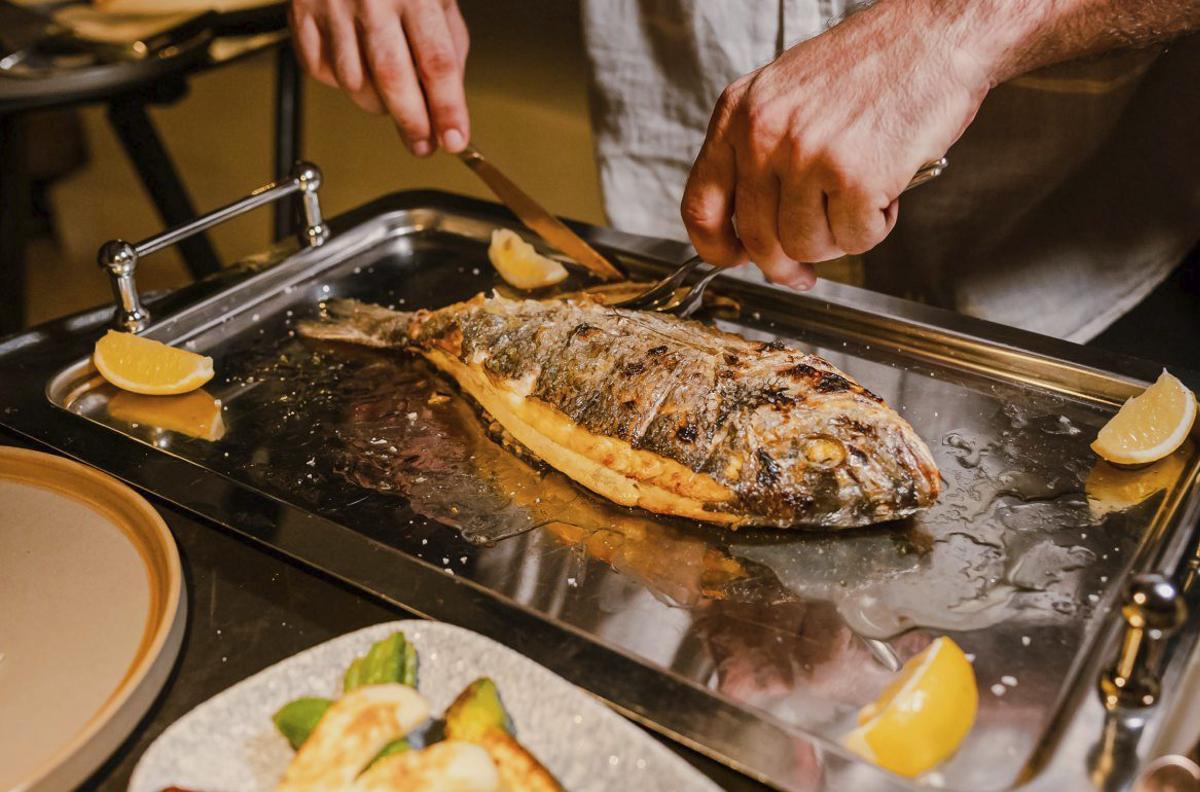 El pescado se prepara a la brasa y se sirve delante del comensal, acompañado de verduras de kilómetro cero.