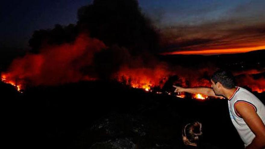 Un vecino señala el fuego, ayer, en Oia. / J.Lores