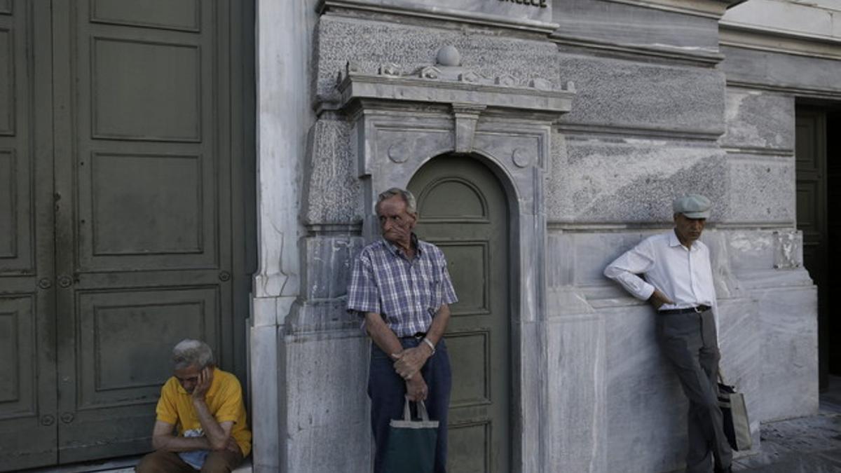 Pensionistas esperan para cobrar frente a un banco de Atenas.