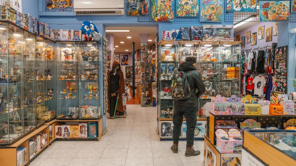 Un cliente observa los objetos de colección que vende Miguel Rodríguez en Crisis Comics.