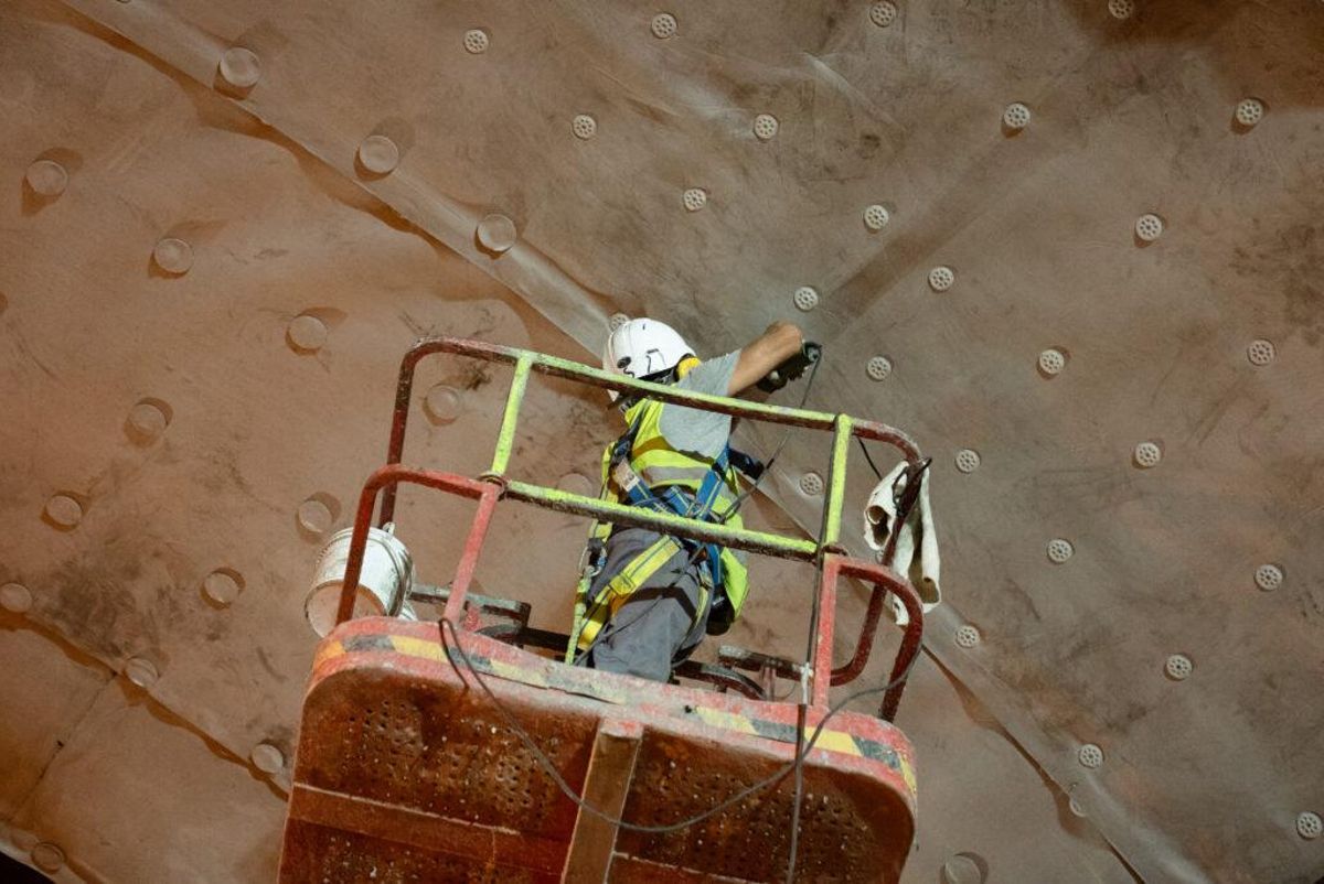 Un operario remacha las lonas de impermeabilización del túnel descendiente