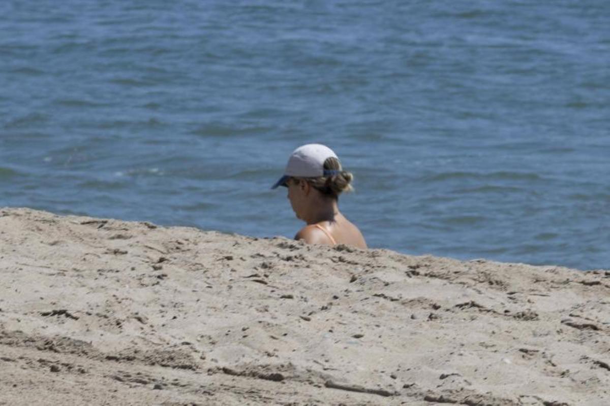 Una mujer camina por la orilla aunque solo se le ve la cabeza por el desnivel existente, este lunes.