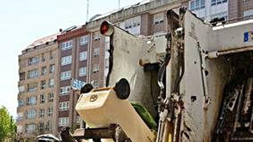 Un trabajador mete basura en un camión.