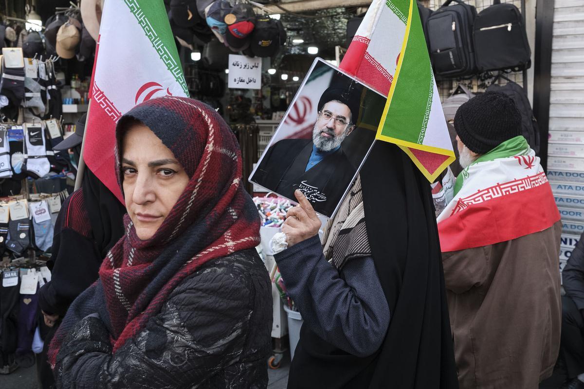 Una mujer participa en los funerales del secretario del Consejo Supremo de Seguridad Nacional, Ali Lariyani, en la plaza Enghelab de Teherán portando una imagen del líder supremo de Irán, Mojtaba Jameneí.