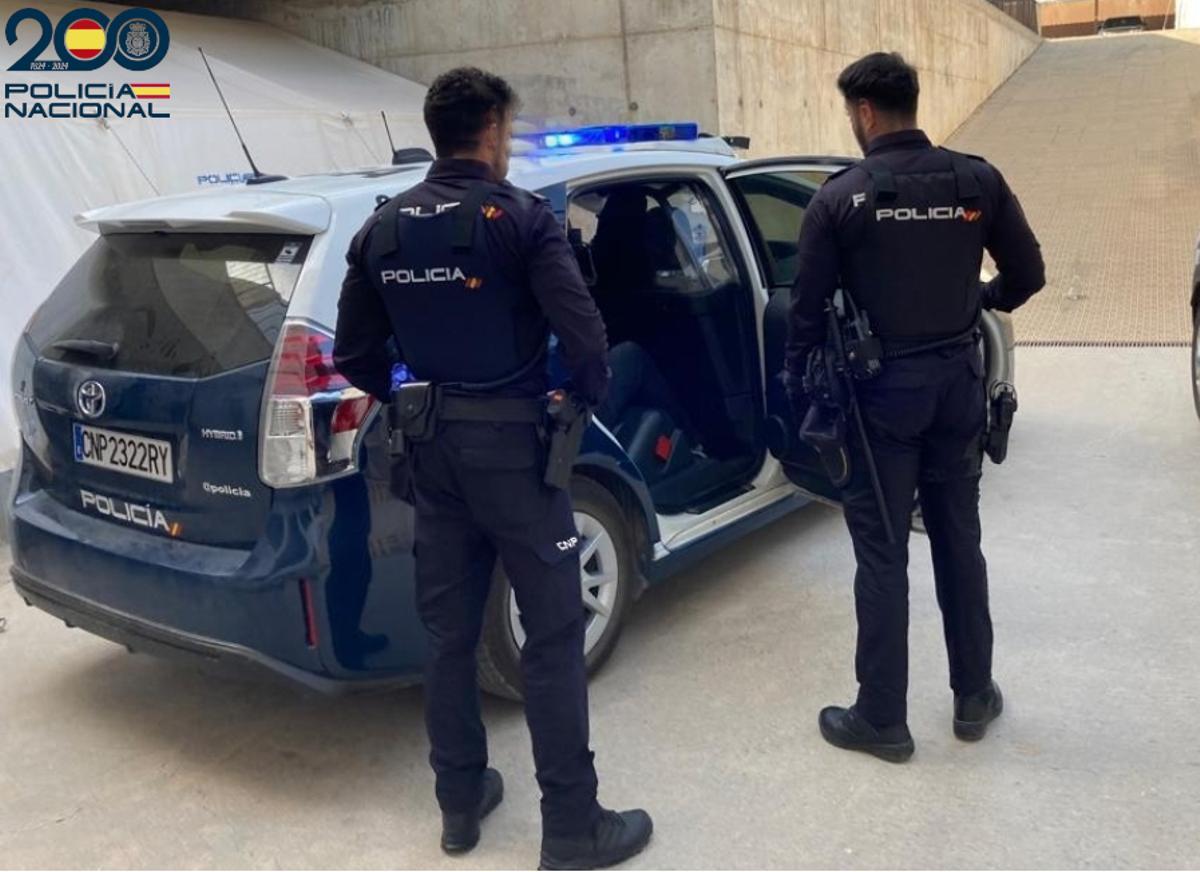 Agentes de la Policía Nacional junto al coche patrulla.