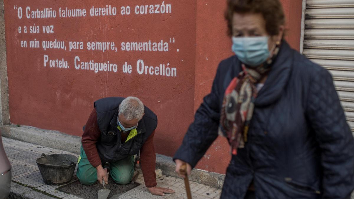 Una mujer camina junto a un operario en O Carballiño, ambos con mascarilla.