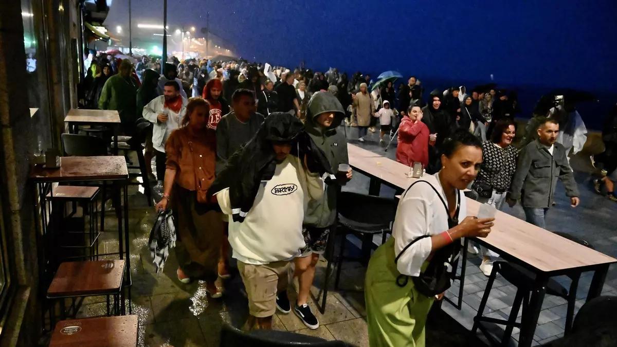 El público abandona la Praza do Mar bajo la lluvia tras suspenderse el concierto de Juan Luis Guerra este sábado por la noche.