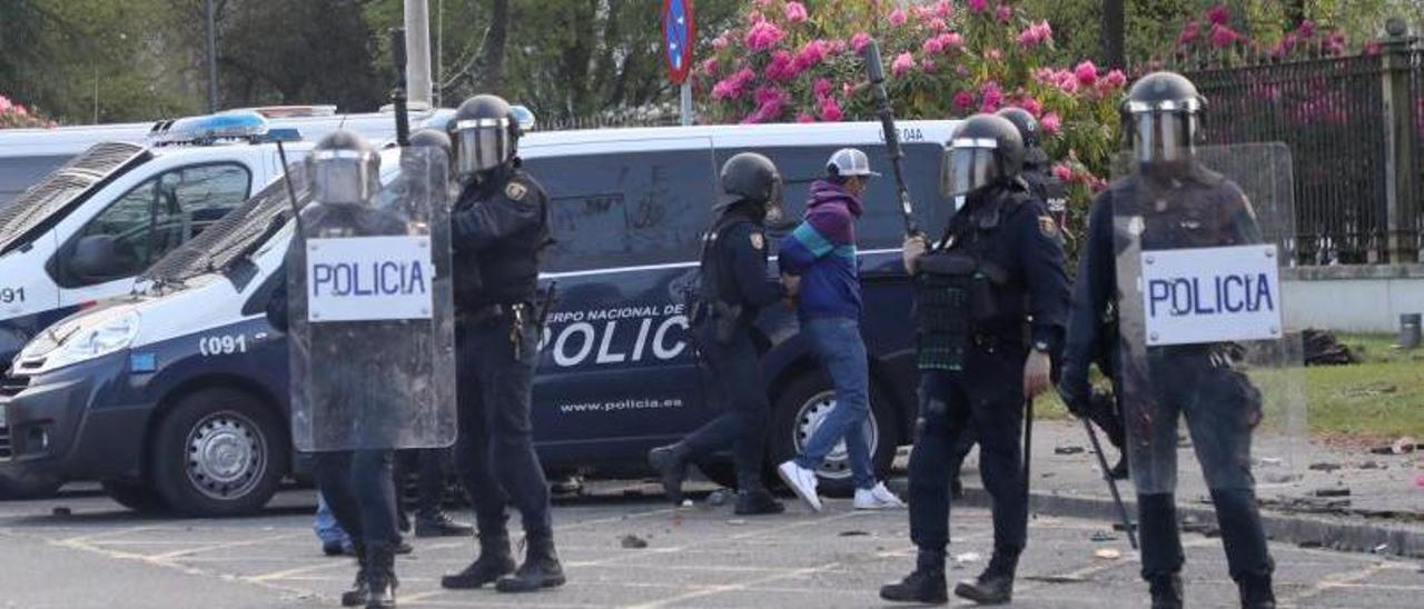 Un policía conduce al furgón a uno de los dos detenidos.