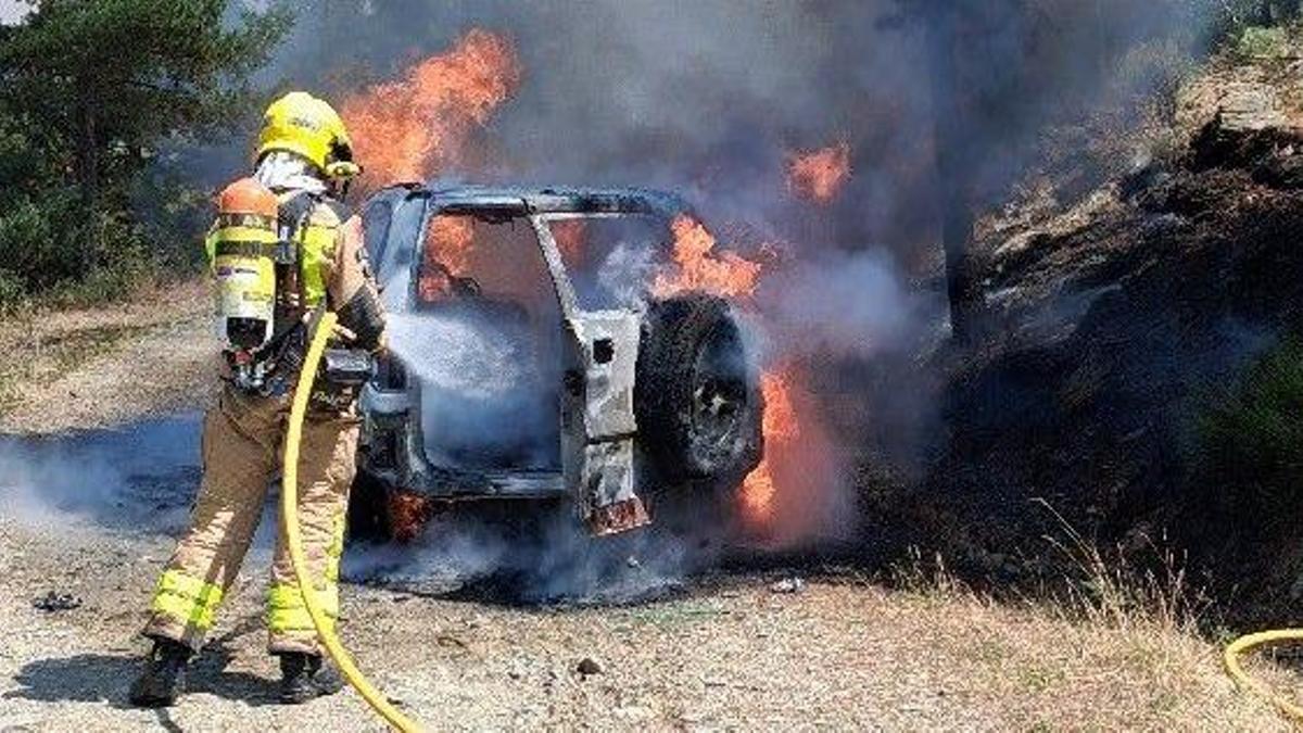 Un bomber treballant en l’extinció del vehicle incendiat a Fontanals de Cerdanya. | Bombers de la Generalitat
