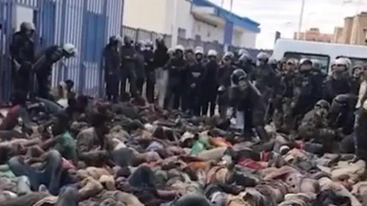 Migrantes subsaharianos yacen en el suelo del patio del puesto fronterizo del Barrio Chino de Nador entre gendarmes marroquís.
