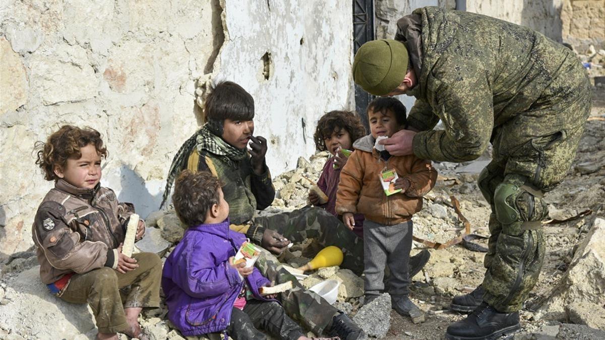 Un militar ruso entrega supuestamente zumo de frutas a niños de Alepo (Siria), en una imagen sin fecha distribuida por el Ministerio de Defensa ruso.