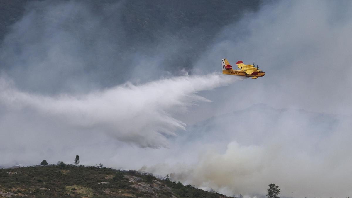 Un hidroavión del servicio de extinción de incendios arroja agua sobre la zona alta del parque de As Fragas do Eume, este martes.