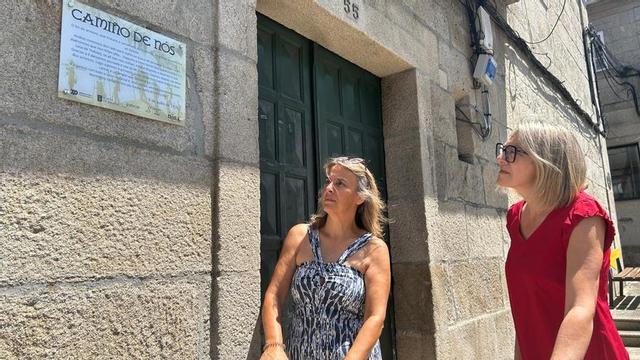 Paula Fernández Pena y Mónica González observan la placa colocada en la antigua sede municipal.  | FIRMA