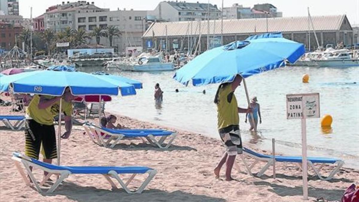 Estacionales 8 Unos trabajadores en la playa de Palamós, el pasado mes de julio.