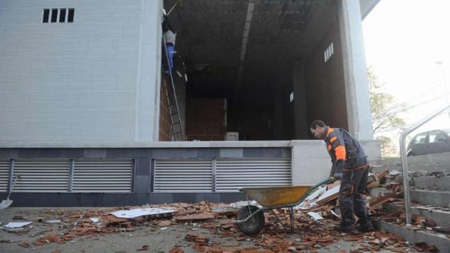 Un operario retira restos del muro que se desprendió del bajo. / juan varela