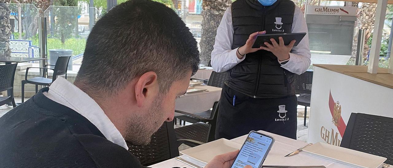 Un cliente observa la carta digital de un restaurante del centro de Elche.