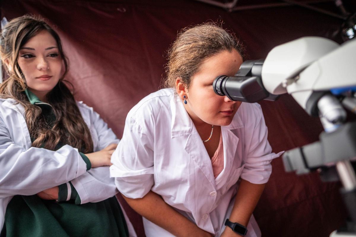 Una joven mira a través del microscopio