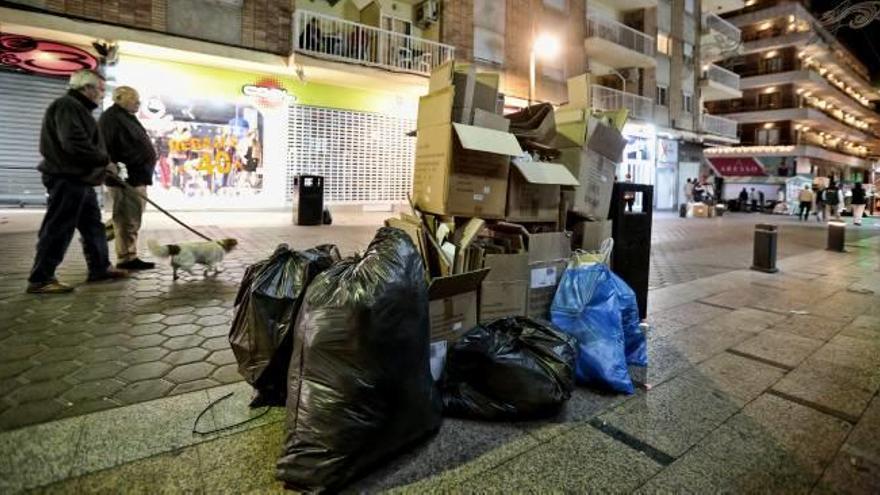 Dos personas pasean junto a la basura acumulada en una de las calles céntricas de Benidorm.