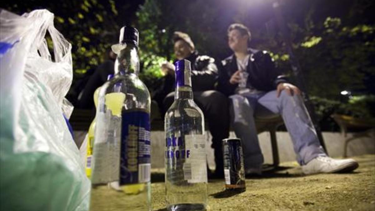 Dos jóvenes beben un banco público durante un botellón en Barcelona