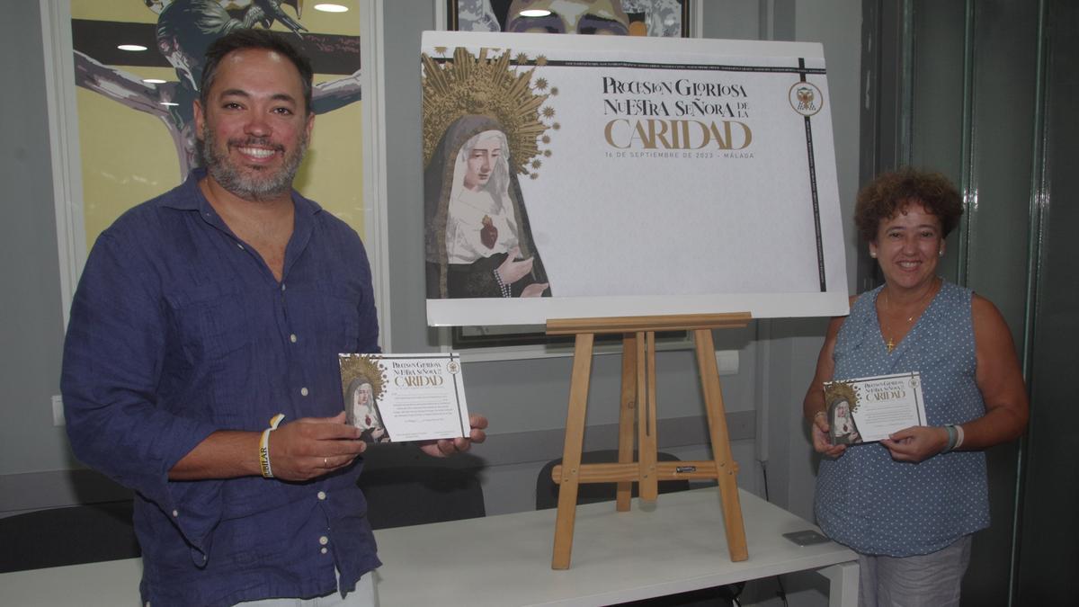 El hermano mayor del Amor, Álvaro Guardiola, con la primera teniente de hermana mayor, Cari Ledesma, muestran el diseño de la papeleta de sitio para la procesión extraordinaria de la Virgen de la Caridad.