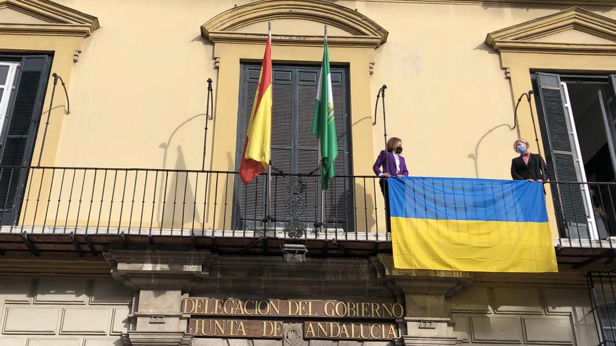 La cónsul ucraniana, Svitlana Kramarenko y la delegada del Gobierno andaluz, Patricia Navarro, ponen la bandera de Ucrania en la Delegación de Málaga.