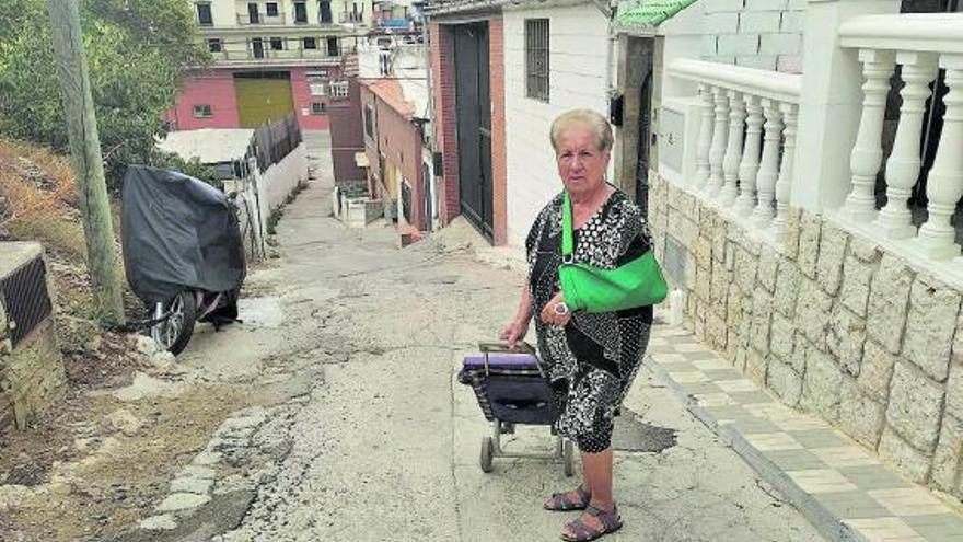 Paquita Gómez, en la calle con el asfaltado en mal estado y su brazo en cabestrillo, tras  resbalarse en mayo.
