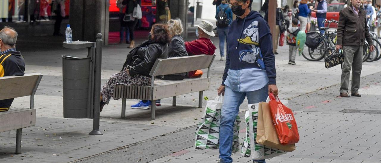 Una mujer carga bolsas en una jornada de compras.