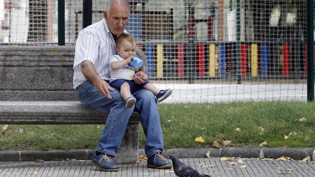 Un abuelo cuida de su nieto en un parque.