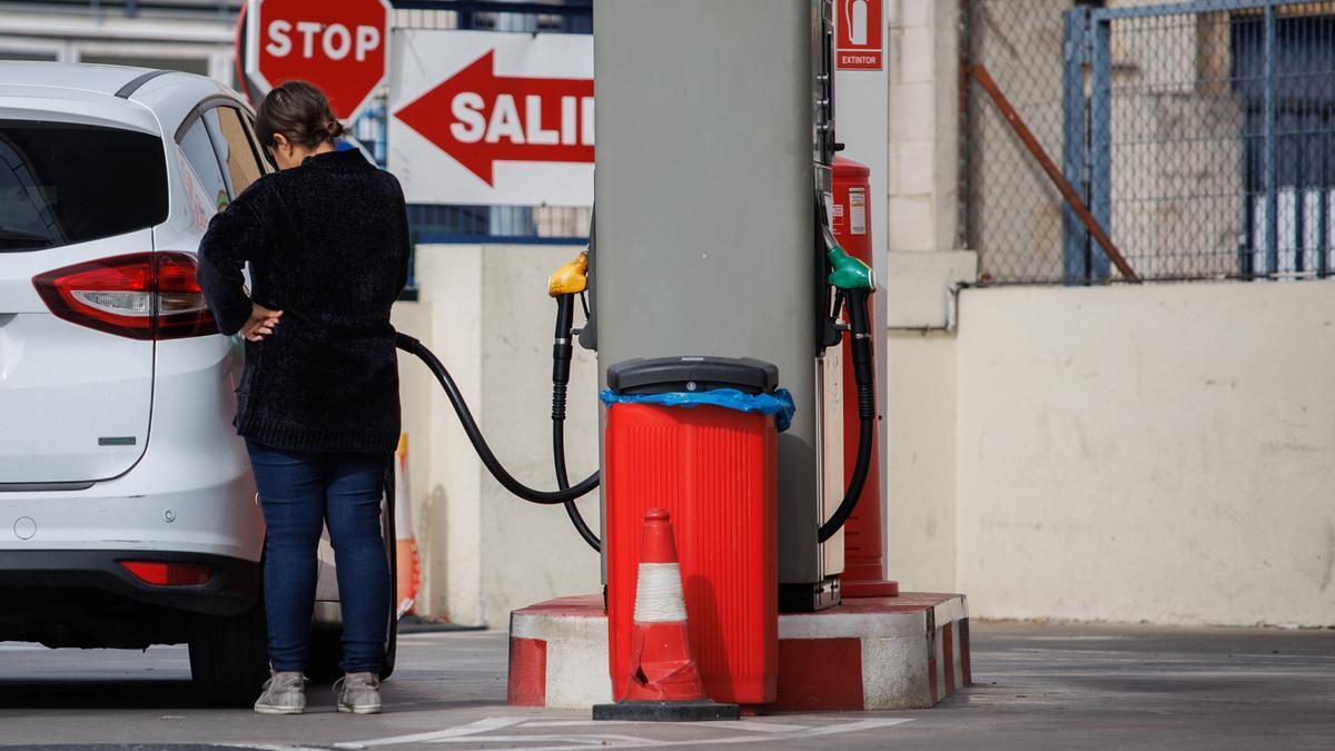 Una mujer pone gasolina en una estación de servicio.