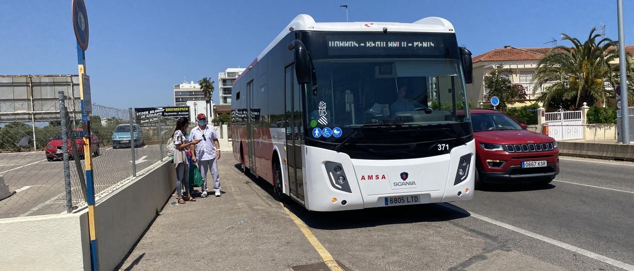 Un grupo de personas espera a que un autobús de línea abra sus puertas en una parada situada en Peñíscola.